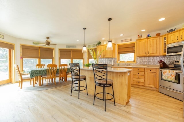 15797 Hillside Dr, Vandalia, MI 49095 - kitchen featuring a kitchen bar, backsplash, light wood-style floors, appliances with stainless steel finishes, and light countertops