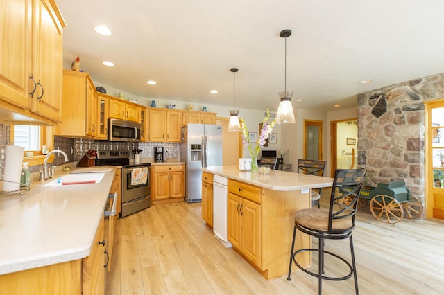15797 Hillside Dr, Vandalia, MI 49095 - kitchen with a breakfast bar area, light wood-type flooring, decorative backsplash, stainless steel appliances, and a sink