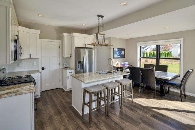 kitchen with tasteful backsplash, dark wood finished floors, stainless steel appliances, white cabinetry, and a sink