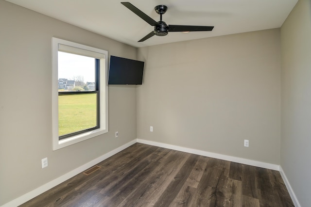 spare room with visible vents, baseboards, dark wood-style floors, and a ceiling fan