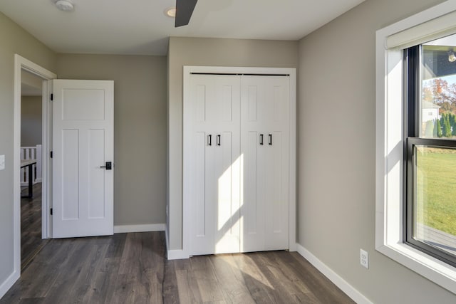 unfurnished bedroom with multiple windows, baseboards, and dark wood-style flooring