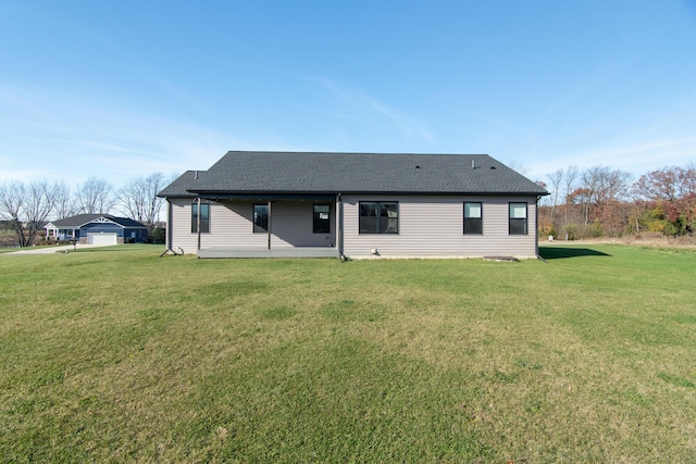 back of property featuring a shingled roof and a yard