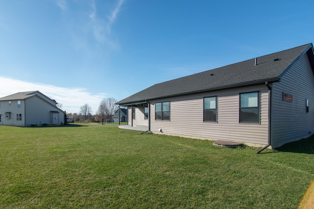 back of house with a lawn and a shingled roof