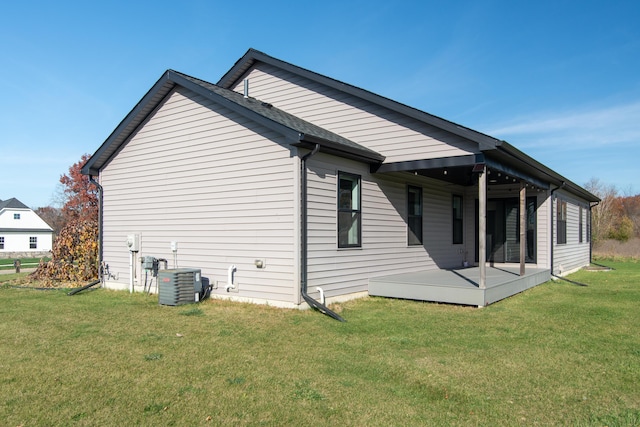 rear view of house with cooling unit and a yard