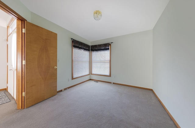 carpeted empty room with baseboards, plenty of natural light, and visible vents