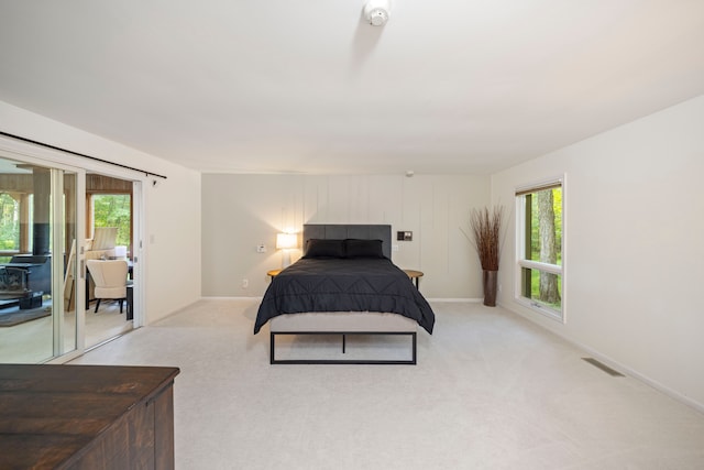 bedroom with visible vents, multiple windows, light carpet, and access to exterior