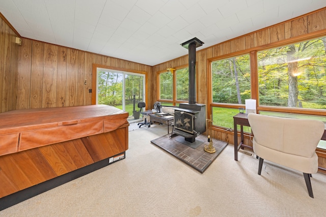 bedroom with a wood stove, wooden walls, carpet flooring, and access to outside