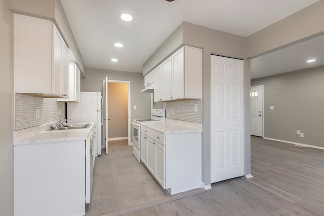 kitchen featuring under cabinet range hood, white cabinets, light countertops, and white electric range