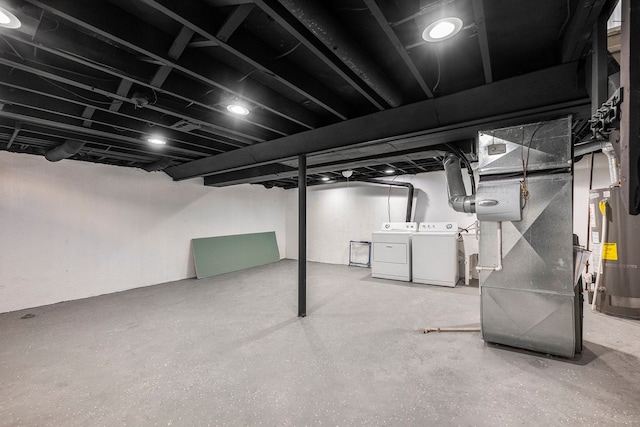 finished basement featuring gas water heater, heating unit, and washing machine and dryer