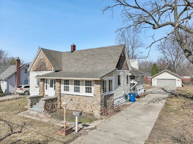 view of front of house with an outbuilding, stone siding, a shingled roof, a garage, and a chimney