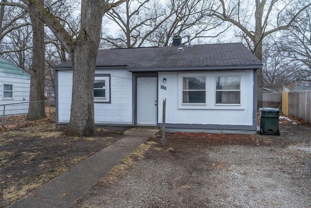 bungalow with a shingled roof and fence