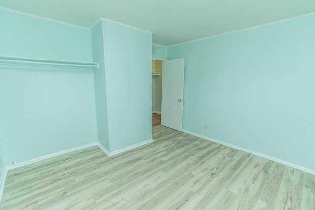 unfurnished bedroom with a closet, crown molding, baseboards, and wood finished floors