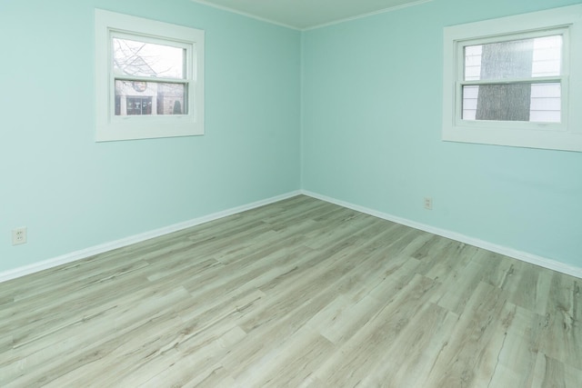 spare room with baseboards, plenty of natural light, wood finished floors, and crown molding