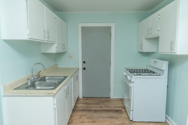 kitchen with light wood finished floors, crown molding, gas range gas stove, light countertops, and a sink