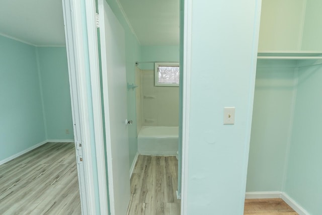 full bath featuring wood finished floors, baseboards, and shower / washtub combination