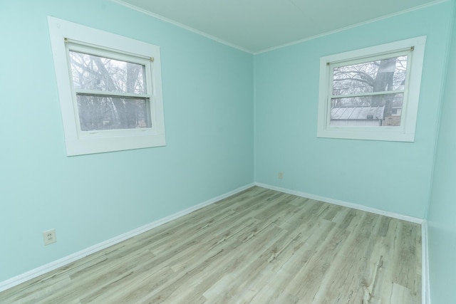 spare room featuring baseboards, wood finished floors, and crown molding