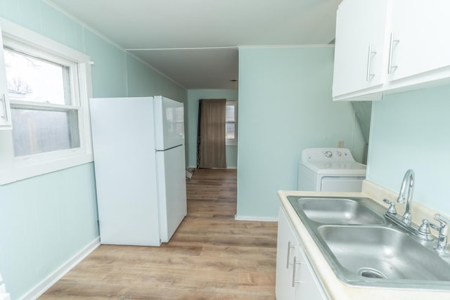 kitchen featuring washer / dryer, white cabinets, freestanding refrigerator, and a sink