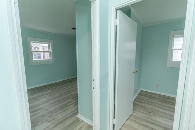 hallway with wood finished floors, baseboards, and ornamental molding