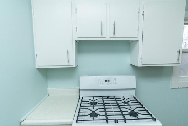 details with white gas stove, white cabinetry, and light countertops