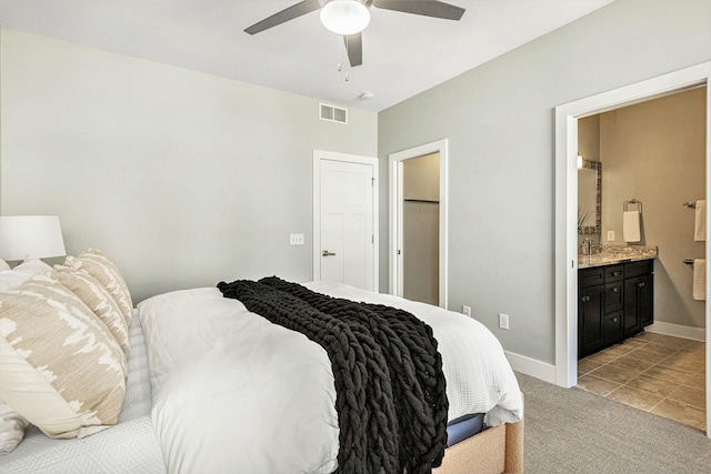 bedroom featuring visible vents, baseboards, light colored carpet, ensuite bathroom, and a ceiling fan