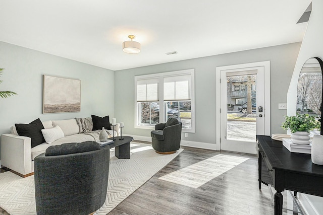 living area with wood finished floors, visible vents, and baseboards