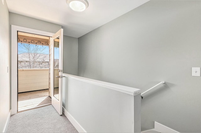 hallway featuring an upstairs landing, carpet flooring, and baseboards