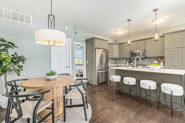 kitchen with visible vents, backsplash, light countertops, gray cabinets, and appliances with stainless steel finishes