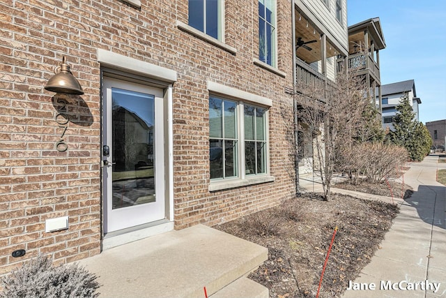 doorway to property featuring brick siding and ceiling fan