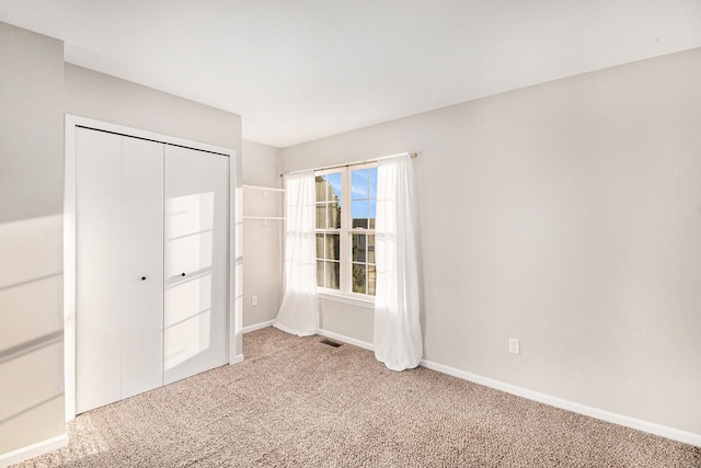 unfurnished bedroom with a closet, visible vents, baseboards, and carpet