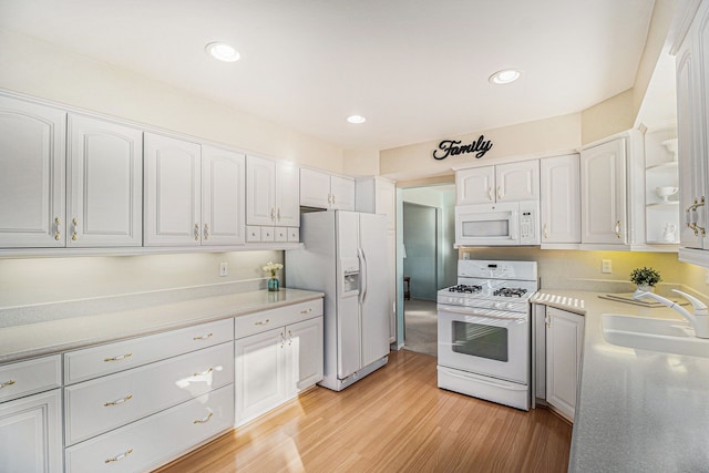 kitchen featuring recessed lighting, light wood-style flooring, white appliances, white cabinetry, and a sink