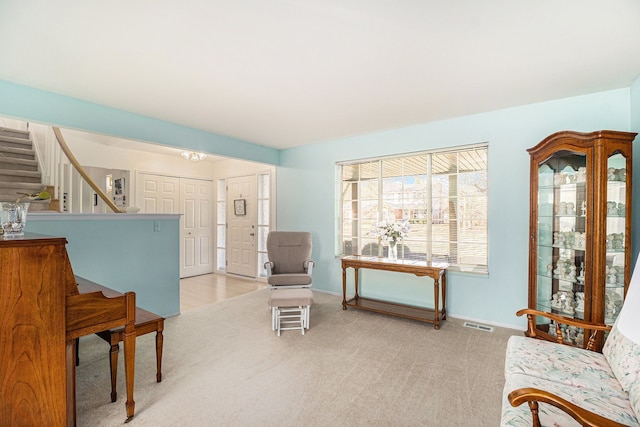 sitting room featuring light carpet, visible vents, stairs, and baseboards