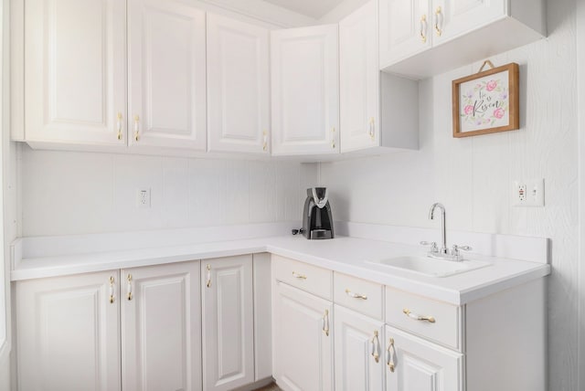 kitchen featuring white cabinetry, light countertops, and a sink