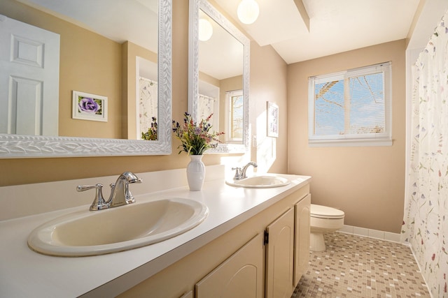 bathroom with a sink, toilet, double vanity, and tile patterned floors