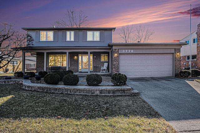 traditional-style house featuring brick siding, covered porch, concrete driveway, and a garage