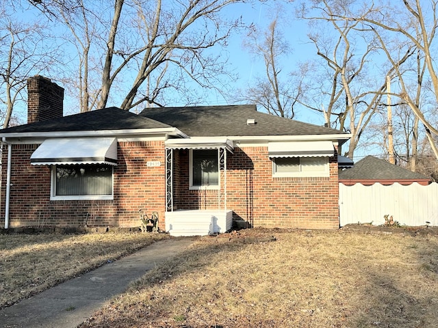 view of side of home featuring fence, brick siding, and a chimney