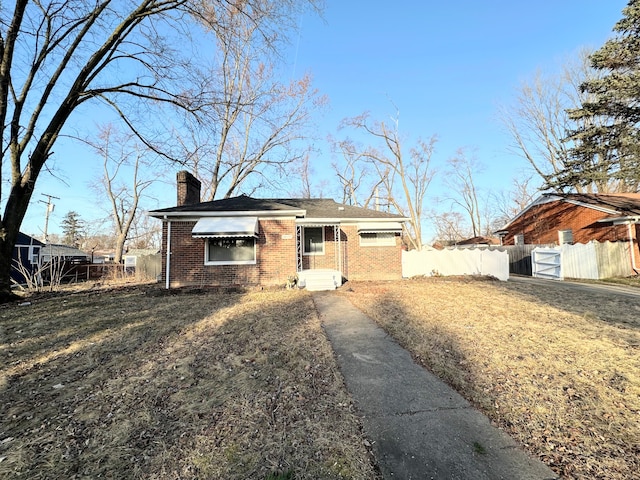 view of front facade with a gate, brick siding, a chimney, and fence