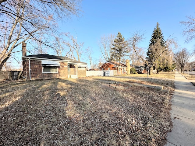 view of front of house featuring fence, brick siding, and a chimney
