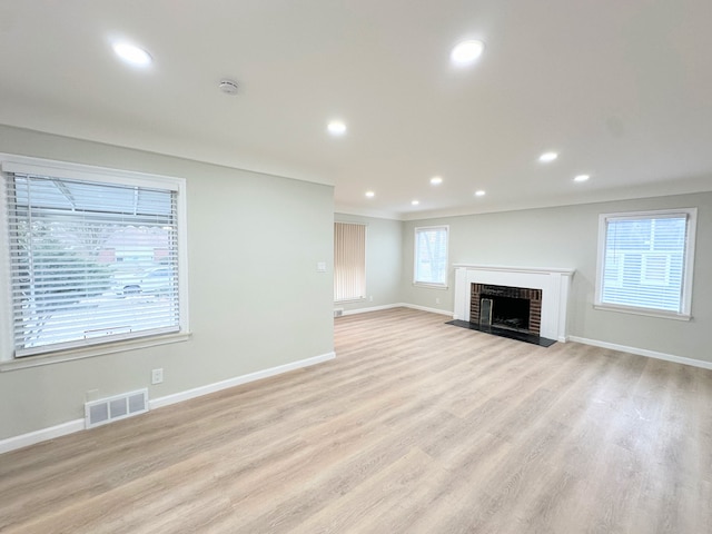 unfurnished living room featuring visible vents, plenty of natural light, baseboards, and light wood-style flooring