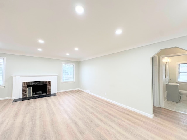 unfurnished living room featuring a fireplace, baseboards, and light wood finished floors