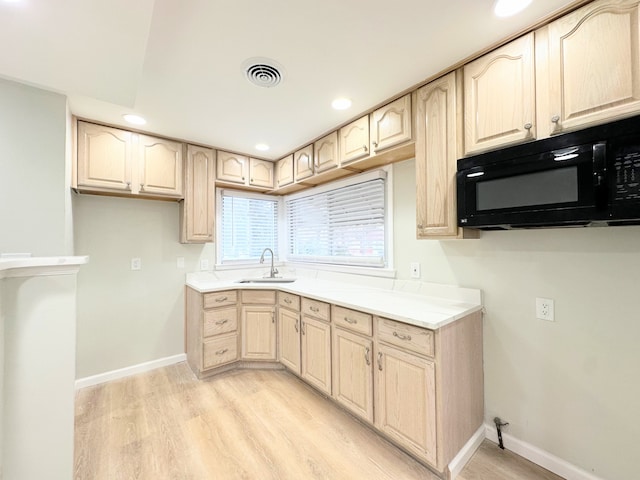 kitchen featuring a sink, visible vents, light wood-type flooring, and black microwave