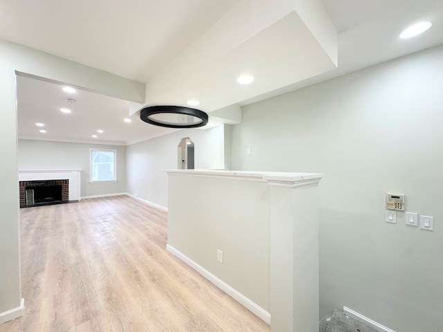 corridor featuring arched walkways, recessed lighting, light wood-type flooring, and baseboards