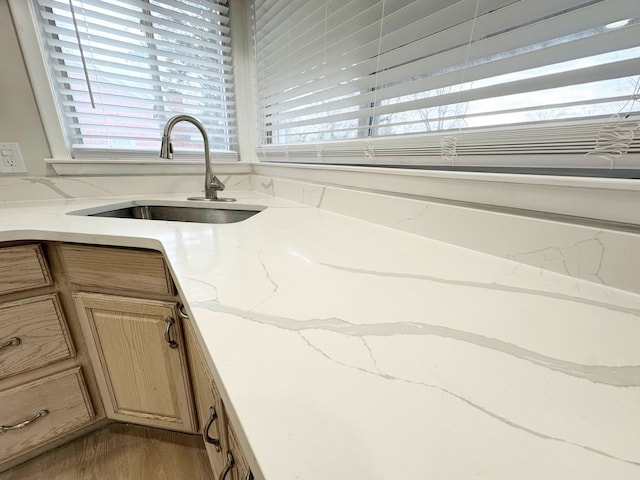 kitchen featuring wood finished floors, light stone countertops, light brown cabinetry, and a sink