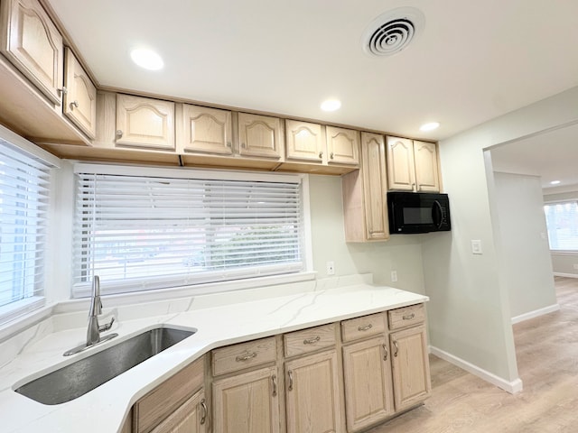 kitchen featuring light stone counters, visible vents, light wood-style flooring, a sink, and black microwave