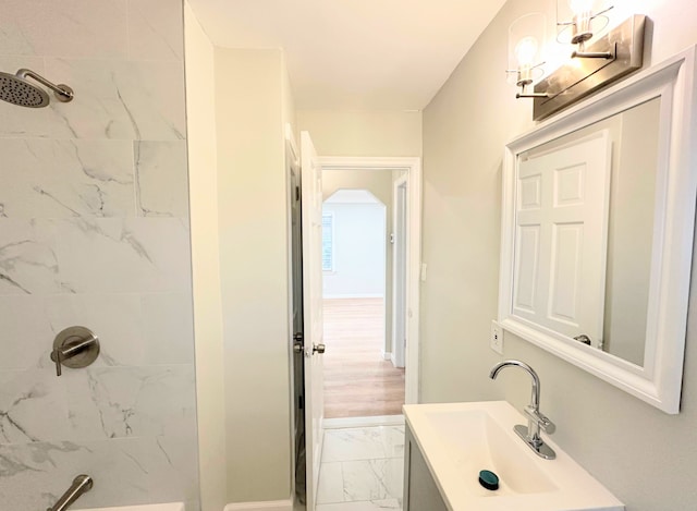 bathroom with marble finish floor, vanity, and a shower