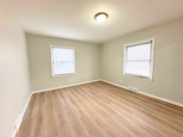 spare room featuring visible vents, a healthy amount of sunlight, baseboards, and light wood-style floors