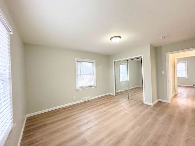 unfurnished bedroom with visible vents, baseboards, a closet, and light wood-style flooring