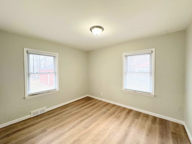 unfurnished room with visible vents, baseboards, and wood finished floors