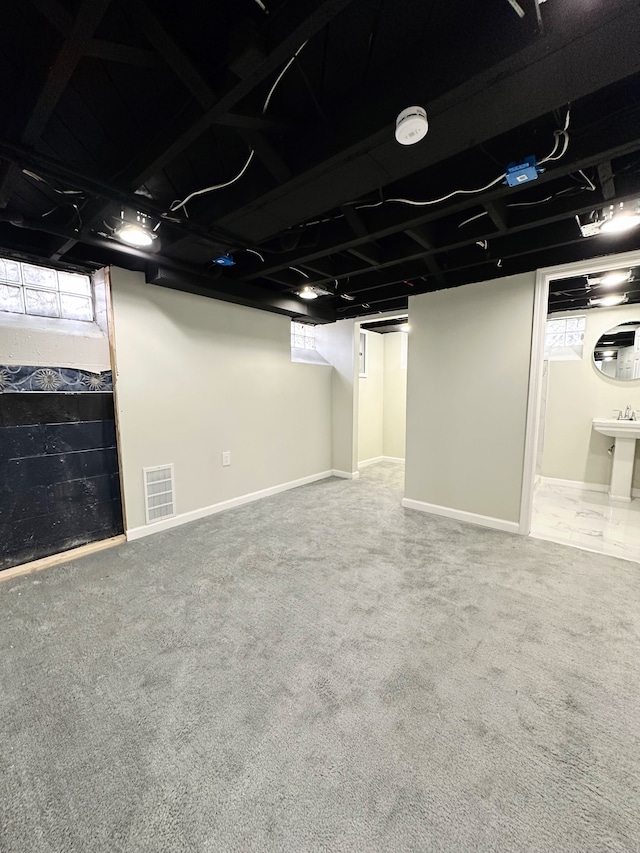 basement featuring visible vents, baseboards, and carpet flooring
