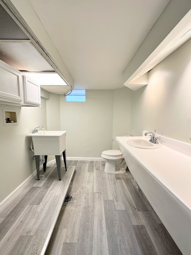bathroom with a sink, baseboards, toilet, and wood finished floors