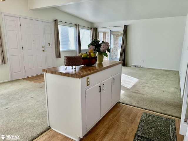 kitchen featuring butcher block countertops, light colored carpet, white cabinets, and visible vents